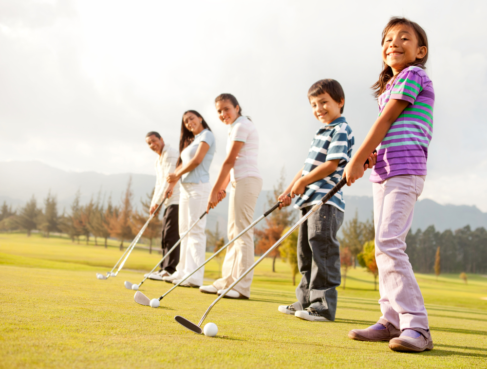 Golf players of all ages practicing to hit the ball at the course