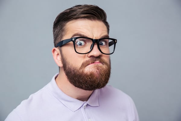Portrait of a funny hipster man looking at camera over gray background